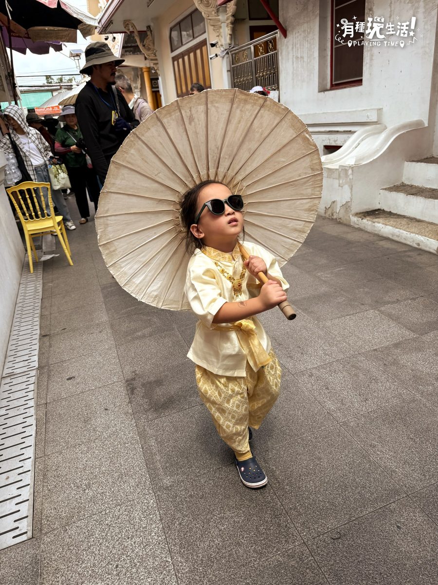 小孩穿鵝黃色泰服撐油紙傘走在鄭王廟旁