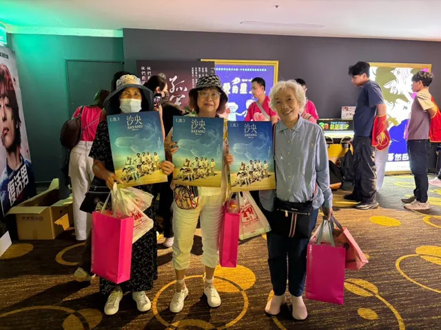 參加《沙央》公益首映的長輩們拿著電影海報合影